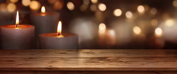 Christmas background with candle lights in front of a wooden table