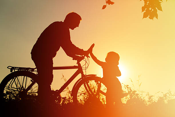 istock father and daughter having fun riding bike at sunset, active 604023192