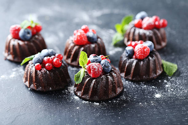 istock Sweet chocolate cakes with berries on black wooden table 604023684