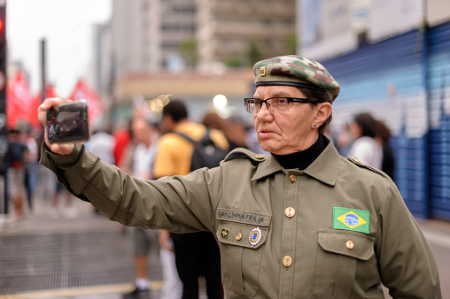 São Paulo, Brazil, September, 11, 2016: Militant far-right which advocates military intervention in the country filming with a mobile protest about 50,000 demonstrators against the coup on Avenida Paulista calling new elections and other patterns of social character.