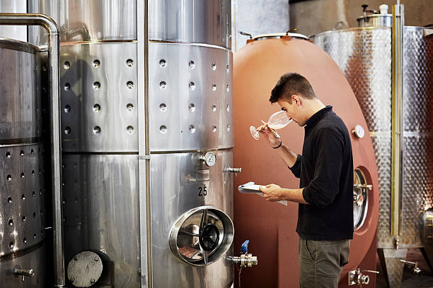 man smelling wine while holding clipboard - 포도주 양조 뉴스 사진 이미지