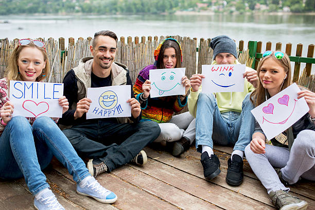 istock Happy friends holding papers with different emoticons. 604026712
