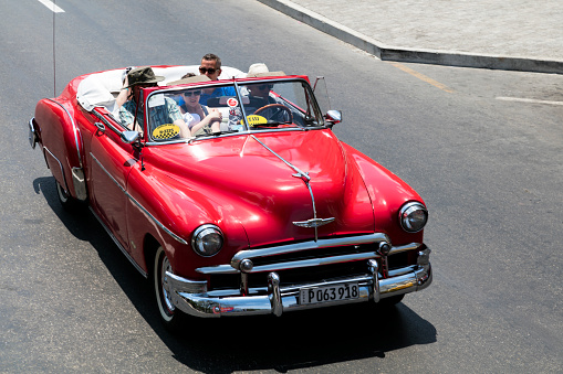 Havana, Сuba - April 13, 2016: Vintage red American car, 1952 Chevrolet Styleline Deluxe Convertible, with tourists, driving down the street in Havana, Cuba, elevated view