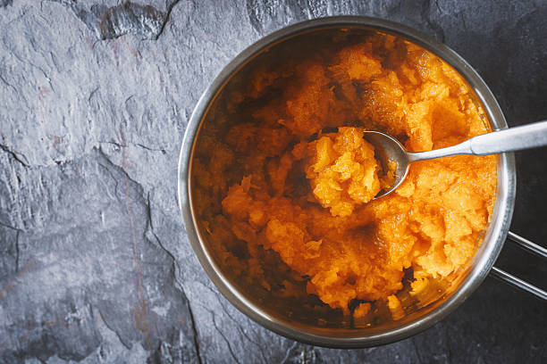 Pumpkin puree in the pot with spoon in the stone background top view horizontal