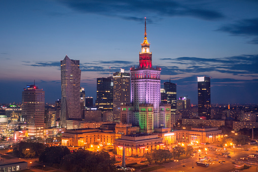 The skyline of central Warsaw at night. Center and in colorful lights stands the Palace of Culture and Science, an example of stalinist architecture from the 1950s.