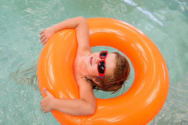 istock Small boy with sunglasses relaxing in swimming pool. 604051326