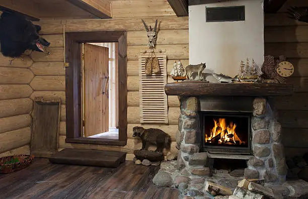 The interior of the hunter's house with burning fireplace and stuffed boar head on the wall .