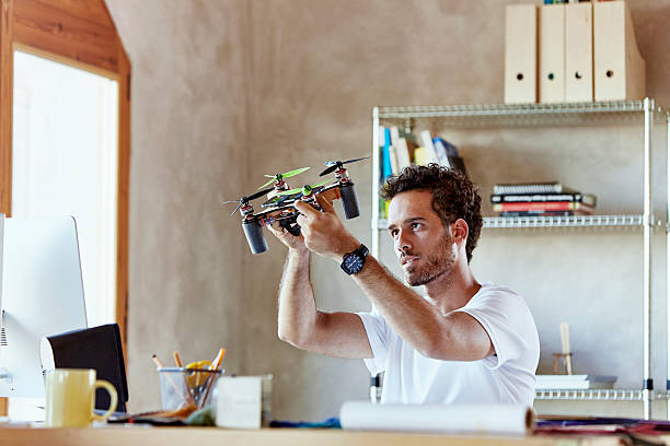 Creative businessman making octocopter in office Creative young businessman making octocopter at desk in office helicopter photos stock pictures, royalty-free photos & images