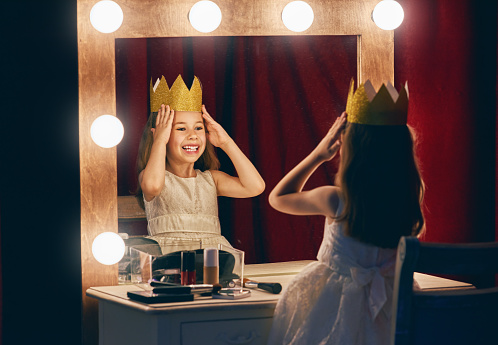 Cute little actress. Child girl in Princess costume on the background of theatrical scenes and mirrors.