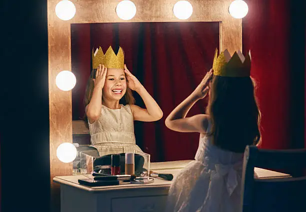 Cute little actress. Child girl in Princess costume on the background of theatrical scenes and mirrors.