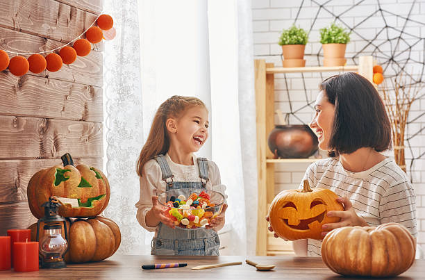 family preparing for Halloween. Happy halloween! A mother and her daughter carving pumpkin. Happy family preparing for Halloween. candy house stock pictures, royalty-free photos & images