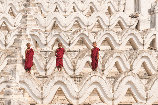 Three Buddhist novices standing on white pagoda in myanmar