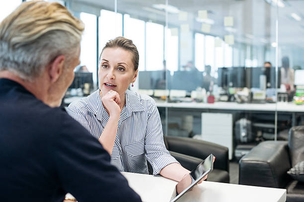 bizneswoman wskazując na tablet i wyjaśniając męskiemu koledze - business togetherness listening people zdjęcia i obrazy z banku zdjęć