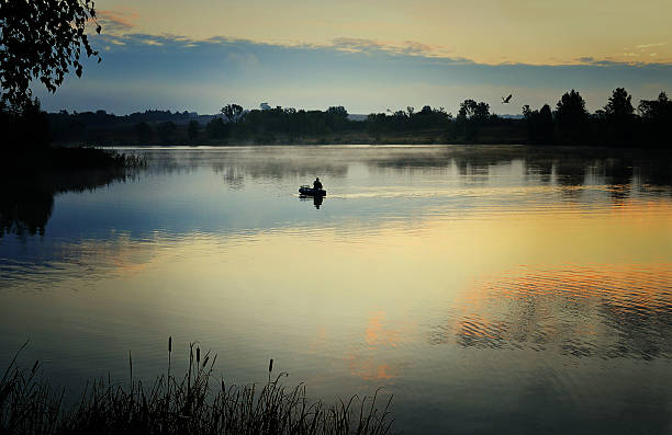 istock Fisherman in a boat sailing in the  mist 604341796