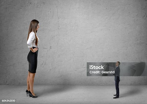 Big Young Businesswoman Standing In Front Of Small Businessman Stock Photo - Download Image Now