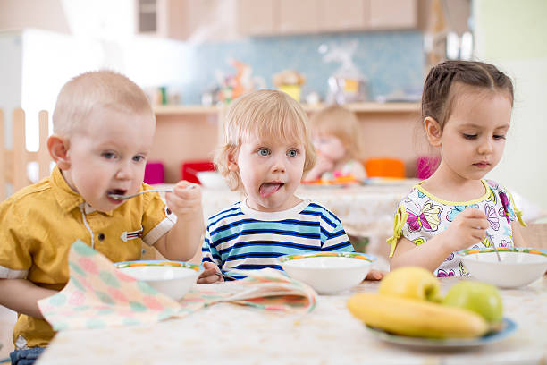 istock three children eating from plates in day care centre 604345088