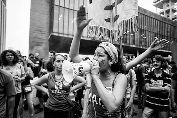 Coup in Brazil São Paulo, Brazil, September, 11, 2016: Woman with a megaphone shouting slogans during act against the coup and calling for new elections and other social agendas for the country militant groups stock pictures, royalty-free photos & images