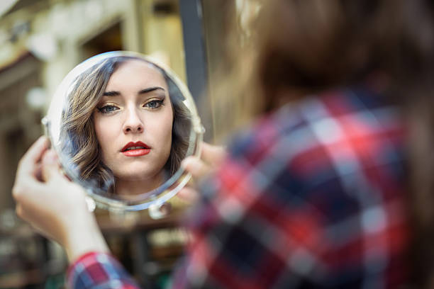 istock Young woman looking at herself in a little mirror 604346278
