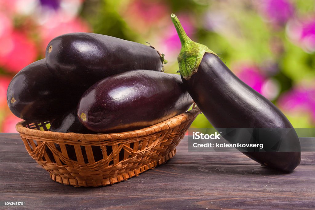 eggplant in a wicker basket on wooden table with blurred eggplant in a wicker basket on a wooden table with a blurred background. Agriculture Stock Photo