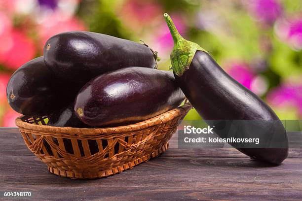 Eggplant In A Wicker Basket On Wooden Table With Blurred Stock Photo - Download Image Now