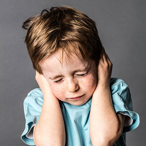 afraid little boy closing ears and eyes against domestic violence frowning little boy closing his ears and eyes against domestic violence or education, afraid of relationship problems, grey background, contrast effects hands covering ears stock pictures, royalty-free photos & images