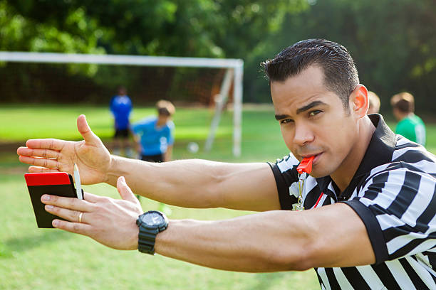 Football referee equipment. Soccer ball and metal whistle on green grass, closeup with space for text