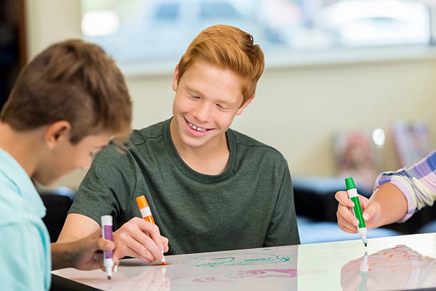 istock Happy red haired teenager working animation station of makerspace class 604355608