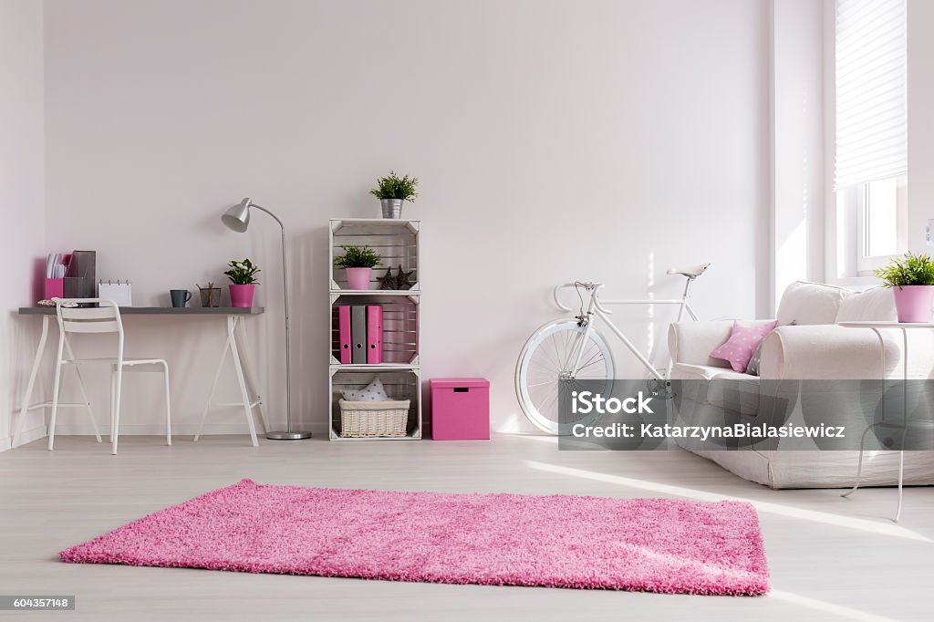 White and pink spacious studio Spacious stylish studio with white walls and pink decorations. Comfortable sofa, vintage bicycle and desk by the wall Apartment Stock Photo