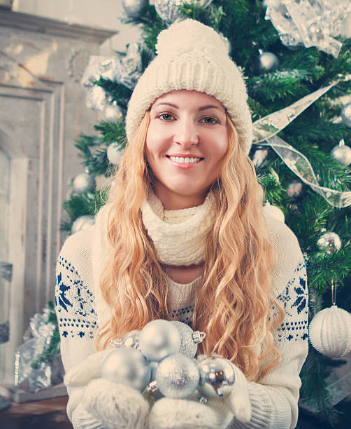 istock Young blond woman holding silver decorative balls wearing white 604358216