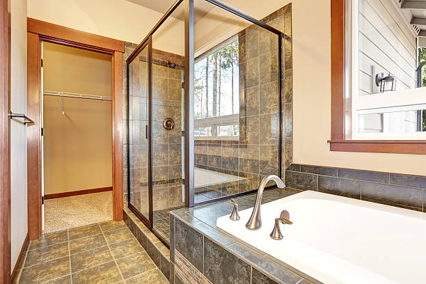 istock Bathroom interior with marble tile trim. View of glass shower 604358554