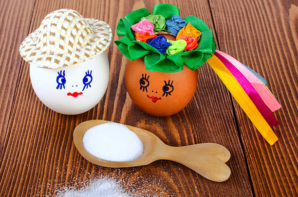 Funny eggs  and wooden spoon with salt. On wooden background.