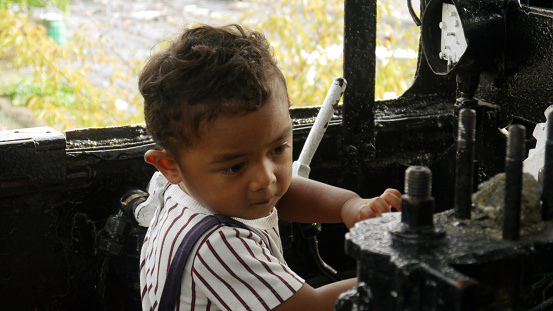 Child is playing in the locomotive in the park.