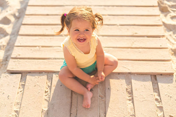 niña sentada en un camino de madera en una playa - beach family boardwalk footpath fotografías e imágenes de stock