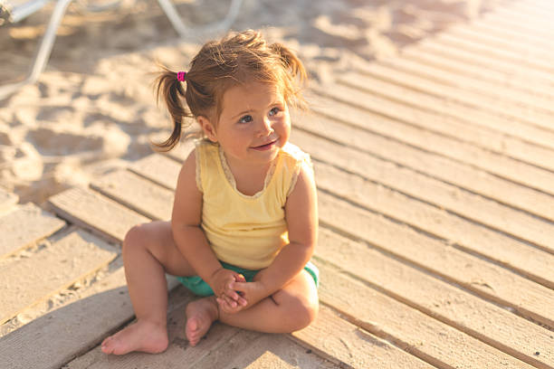 niña sentada en un camino de madera en una playa - beach family boardwalk footpath fotografías e imágenes de stock