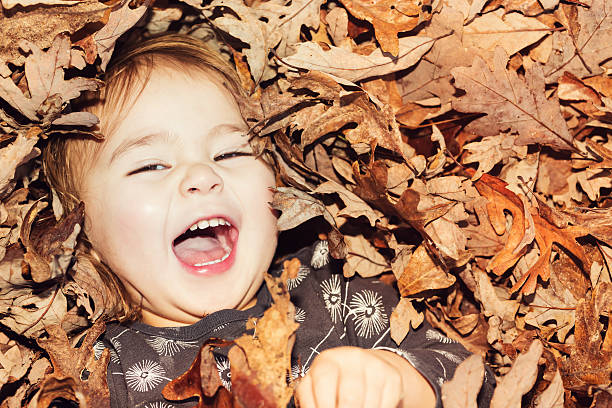 istock Happy toddler girl smiling while lying in big pile 604370412