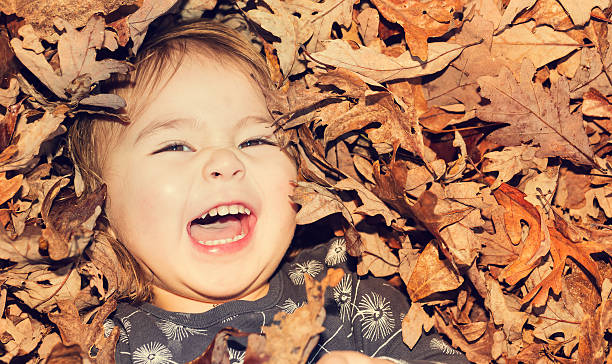 istock Happy toddler girl smiling while lying down in a pile 604370480