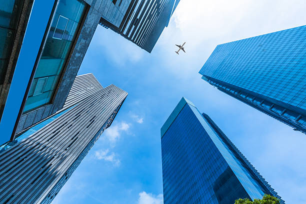 istock Skyscrapers with a flying airplane against blue sky 604371386