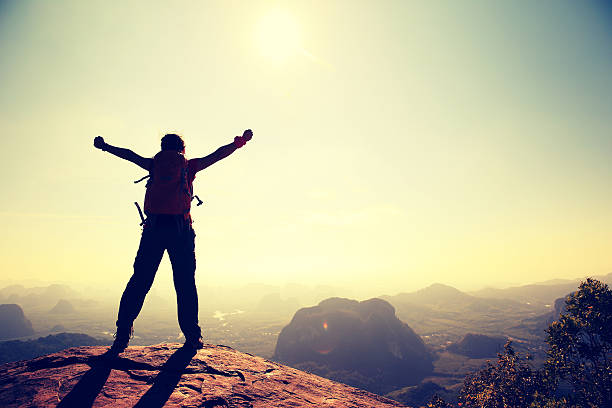 istock cheering woman hiker at sunrise mountain peak 604371888