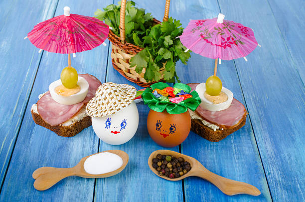 Funny eggs in the hat and wreath. With sandwiches and umbrellas. With basket with parsley and spices in a wooden spoon.