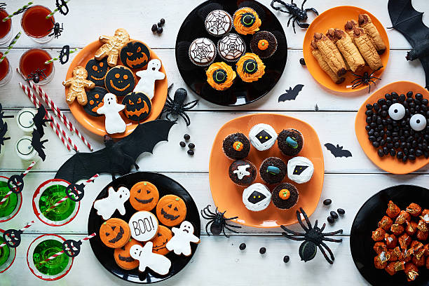 Table full of Halloween sweets High angle view of Halloween cookies, candies, cupcakes, drinks on decorated table halloween cupcake stock pictures, royalty-free photos & images