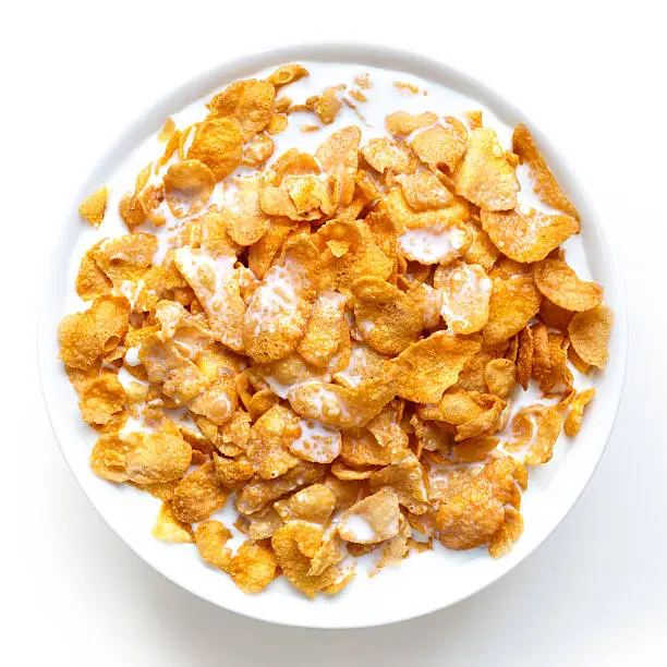 Bowl of cornflakes in milk isolated on white from above.