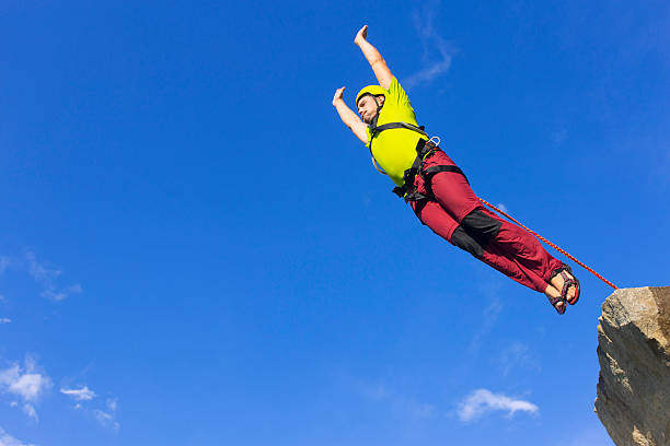 A young man hanging on a bungee cord after a scary jump.