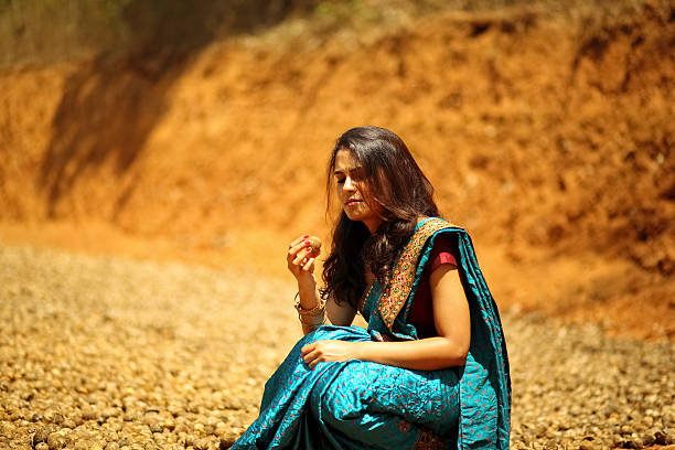 Female agriculturist wearing saree inspecting the stockpile of arecanut.