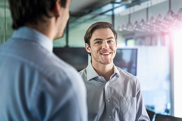 istock Smiling young businessman looking at colleague 604823218