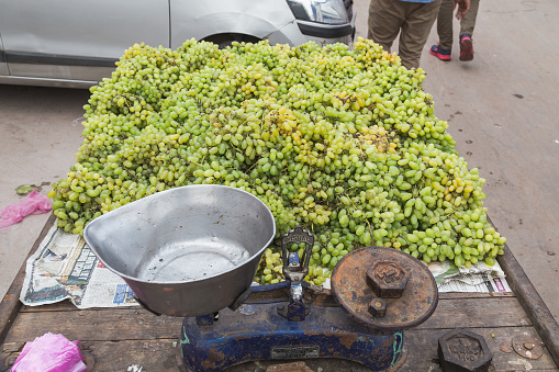 Delhi, India - March 19, 2016: Large amounts of green grapes and scales a street stall in India.