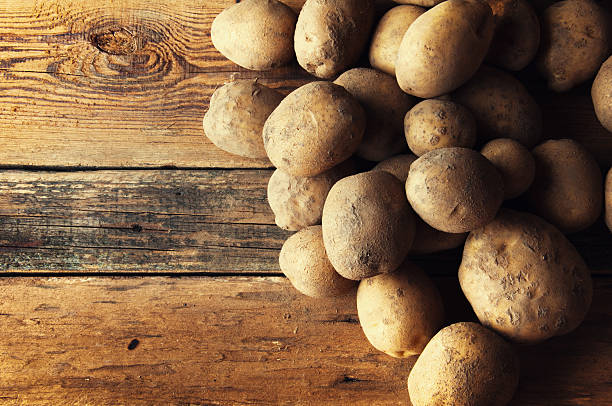 istock Potetoes on wooden table. Copyspace 604825780