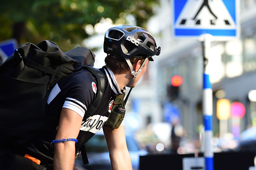 Stockholm, Sweden - September 13, 2016: Delivery bike in action, courier for Ryska Posten company. Young man wearing helmet, fast pace in central Stockholm