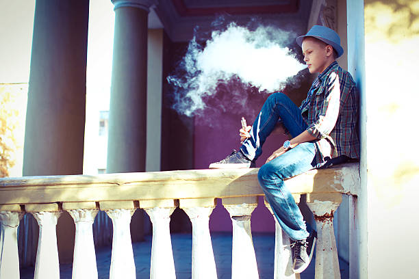 Health problems and social issues. Teenagers smoking electronic cigarette in park
