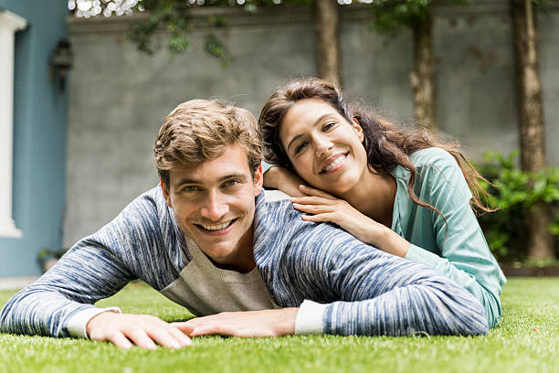istock Smiling young couple lying on grass in backyard 604833250