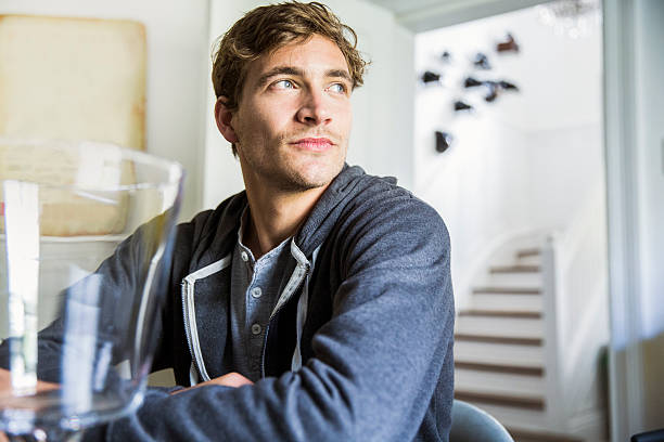 Thoughtful young man looking away at home